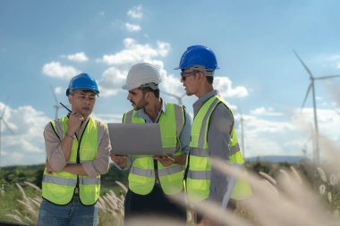 Saha görevinde çalışan Asyalı mühendis. İşçiler inşaat alanının etrafındaki inşaat ve makineleri kontrol ediyorlar. Temiz enerji ve çevresel sürdürülebilir elektrik için rüzgar türbini.