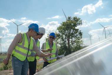 Mühendis, güneş pili paneli veya fotovoltaik hücrenin yapımını elektronik cihazla denetliyor. Yeşil enerjinin endüstriyel yenilenebilir enerjisi. Kule çatısında çalışan fabrika işçisi.