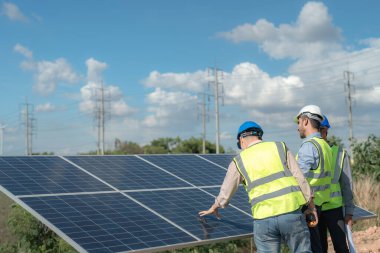 Mühendis, güneş pili paneli veya fotovoltaik hücrenin yapımını elektronik cihazla denetliyor. Yeşil enerjinin endüstriyel yenilenebilir enerjisi. Kule çatısında çalışan fabrika işçisi.