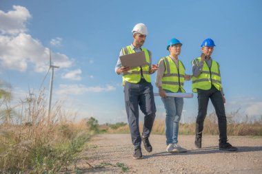 Saha görevinde çalışan Asyalı mühendisler. Çalışanlar proje alanının etrafındaki inşaat ve makineleri inceliyor. Temiz kaynak enerjisi ve çevresel sürdürülebilir rüzgar türbini elektriği.