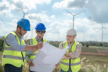 Saha görevinde çalışan Asyalı mühendis. İşçiler inşaat alanının etrafındaki inşaat ve makineleri kontrol ediyorlar. Temiz enerji ve çevresel sürdürülebilir elektrik için rüzgar türbini.