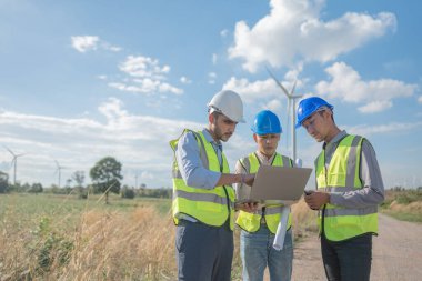 Saha görevinde çalışan Asyalı mühendisler. Çalışanlar proje alanının etrafındaki inşaat ve makineleri inceliyor. Temiz kaynak enerjisi ve çevresel sürdürülebilir rüzgar türbini elektriği.