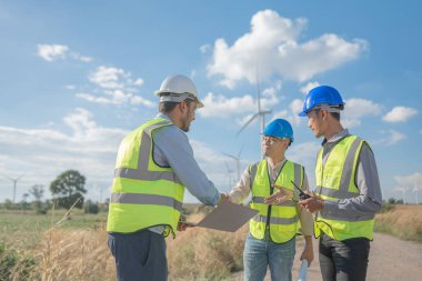 Saha görevinde çalışan Asyalı mühendisler. Çalışanlar proje alanının etrafındaki inşaat ve makineleri inceliyor. Temiz kaynak enerjisi ve çevresel sürdürülebilir rüzgar türbini elektriği.