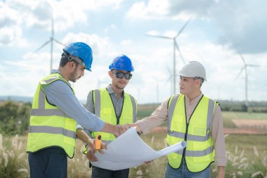 Saha görevinde çalışan Asyalı mühendis. İşçiler inşaat alanının etrafındaki inşaat ve makineleri kontrol ediyorlar. Temiz enerji ve çevresel sürdürülebilir elektrik için rüzgar türbini.