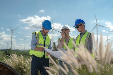 Saha görevinde çalışan Asyalı mühendis. İşçiler inşaat alanının etrafındaki inşaat ve makineleri kontrol ediyorlar. Temiz enerji ve çevresel sürdürülebilir elektrik için rüzgar türbini.