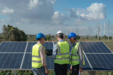 Mühendis, güneş pili paneli veya fotovoltaik hücrenin yapımını elektronik cihazla denetliyor. Yeşil enerjinin endüstriyel yenilenebilir enerjisi. Kule çatısında çalışan fabrika işçisi.