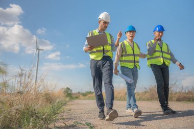 Saha görevinde çalışan Asyalı mühendisler. Çalışanlar proje alanının etrafındaki inşaat ve makineleri inceliyor. Temiz kaynak enerjisi ve çevresel sürdürülebilir rüzgar türbini elektriği.