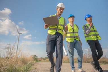 Saha görevinde çalışan Asyalı mühendisler. Çalışanlar proje alanının etrafındaki inşaat ve makineleri inceliyor. Temiz kaynak enerjisi ve çevresel sürdürülebilir rüzgar türbini elektriği.