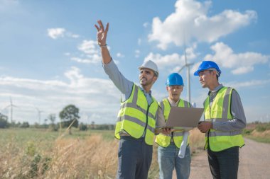 Saha görevinde çalışan Asyalı mühendisler. Çalışanlar proje alanının etrafındaki inşaat ve makineleri inceliyor. Temiz kaynak enerjisi ve çevresel sürdürülebilir rüzgar türbini elektriği.