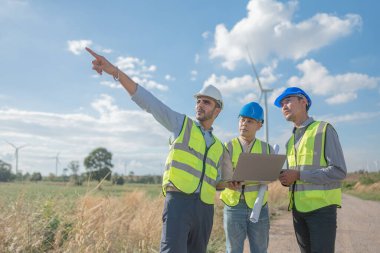 Saha görevinde çalışan Asyalı mühendisler. Çalışanlar proje alanının etrafındaki inşaat ve makineleri inceliyor. Temiz kaynak enerjisi ve çevresel sürdürülebilir rüzgar türbini elektriği.