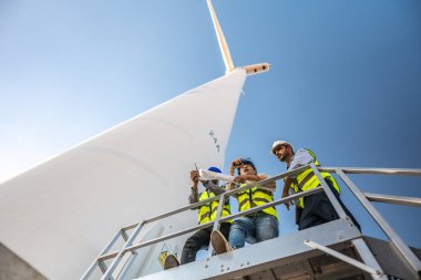 Saha görevinde çalışan Asyalı mühendisler. İşçiler inşaat alanının etrafındaki inşaat ve makineleri kontrol ediyorlar. Temiz enerji ve çevresel sürdürülebilir elektrik için rüzgar türbini.