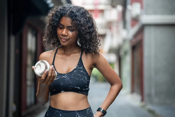 African woman sport healthy fit and firm slim drink water from cup on the hand. athletic running wearing in the sportswear at city and town. Fitness and sport motivation. Runner concept.