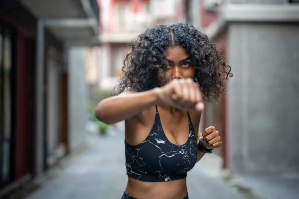 Attractive and strong African woman stretching before fitness at outdoor city. Sports concept. Healthy lifestyle. woman warm up by boxing in the air.