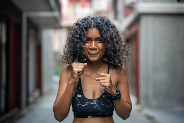 Attractive and strong African woman stretching before fitness at outdoor city. Sports concept. Healthy lifestyle. woman warm up by boxing in the air.