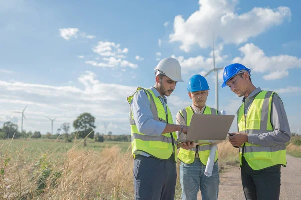 Asian engineers working in fieldwork outdoor. Workers walking and inspect construction and machine around project site. Wind turbine electrical of clean resource enerdy and environment sustainable.