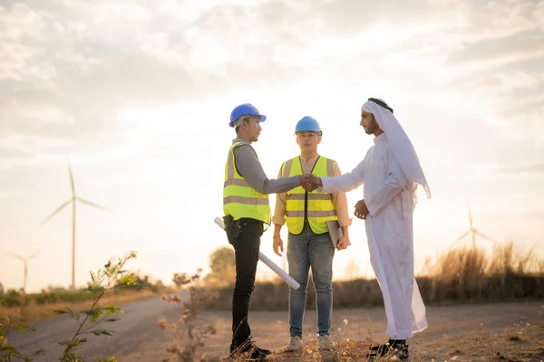 日没の空で建設中のアジアのエンジニアとアラブのビジネスマンのチェックと検査 人が操作する クリーンエネルギーと環境の電気のための風力タービン 持続可能な産業 — ストック写真