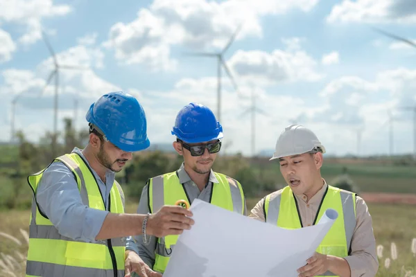 Asian engineer working in fieldwork outdoor. Workers check and inspect construction and machine around building project site. Wind turbine for electrical of clean energy and environment sustainable.
