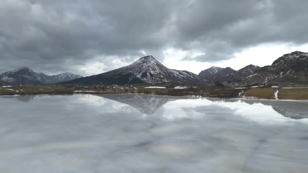 雪の山の頂上と美しい白い冬の不思議の国の風景のパノラマビューは 空と雲と冷たい晴れた日に透明な氷の湖に反映されます ノルウェーのフィヨルド山 — ストック動画