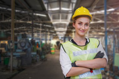 El yapımı kadın işçinin portresi mavi çalışma odası elbisesi ve güvenlik kaskı ile ağır sanayi fabrikası için gerekli ekipman ile ayakta duruyor. Çelik fabrikası.