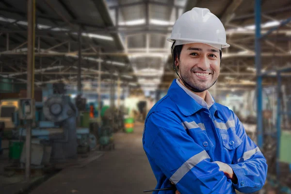 Portrait of manual man worker is standing with confident with blue working suite dress and safety helmet in front machine and equipment for heavy industry factory. Steel plant for production.
