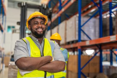 İş elbisesi ve kaskı giyen Afrikalı erkek işçi fabrika deposunda çalışıyor. Denetim kalite denetimi.