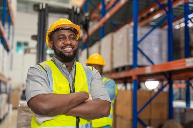 İş elbisesi ve kaskı giyen Afrikalı erkek işçi fabrika deposunda çalışıyor. Denetim kalite denetimi.
