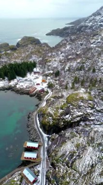 Nusfjord otantik balıkçı köyünün kışın gün batımında geleneksel kırmızı rorbu evleri ile en iyi hava manzarası. Lofoten adaları. Norveç. Dağ ve mavi deniz suyunun manzarasının en üst görüntüsü.