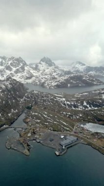 Nusfjord otantik balıkçı köyünün kışın gün batımında geleneksel kırmızı rorbu evleri ile en iyi hava manzarası. Lofoten adaları. Norveç. Dağ ve mavi deniz suyunun manzarasının en üst görüntüsü. 