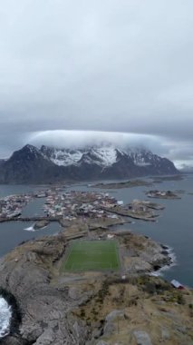 Nusfjord otantik balıkçı köyünün kışın gün batımında geleneksel kırmızı rorbu evleri ile en iyi hava manzarası. Lofoten adaları. Norveç. Dağ ve mavi deniz suyunun manzarasının en üst görüntüsü. 