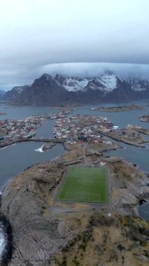 Nusfjord otantik balıkçı köyünün kışın gün batımında geleneksel kırmızı rorbu evleri ile en iyi hava manzarası. Lofoten adaları. Norveç. Dağ ve mavi deniz suyunun manzarasının en üst görüntüsü. 