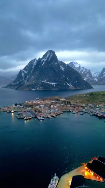 ロフテン島ノルウェーの空中ビュー 雪景色の山のピークとラインの日没の漁村の冬の季節 ノルウェーでは赤の家がある 冬に雪が降ると — ストック動画