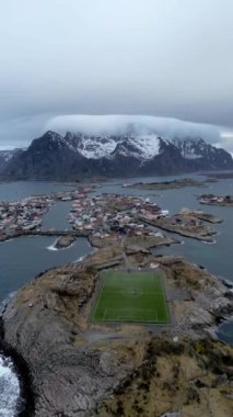 Nusfjord otantik balıkçı köyünün kışın gün batımında geleneksel kırmızı rorbu evleri ile en iyi hava manzarası. Lofoten adaları. Norveç. Dağ ve mavi deniz suyunun manzarasının en üst görüntüsü. 