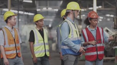 Çeşitli fabrika çalışanlarından oluşan bir grup yerel depoyu teftiş ediyor ve kontrol ediyor. Asyalı, beyaz, beyaz ve Asyalı insanlar ağır makine fabrikasında. Konsept Mühendisi İşletim ve Kontrol.
