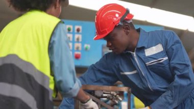 Fabrika Profesyonel Afrikalı ve Asyalı işçi ve makinede yönetici müfettişi ve fabrika çevresindeki teftişi tartışıyorlar. Operasyondan önce kalite ve yetkilendirme testleri için tamir edilen ekip mühendisleri.