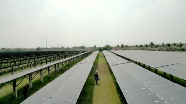 Mühendis kadın güneş pili panelinin yapımını denetliyor. Yeşil enerjinin endüstriyel yenilenebilir enerjisi. Güneş pili panelinin güneş çiftliğindeki en üst hava görüntüsü. Endüstriyel yenilenebilir enerji.