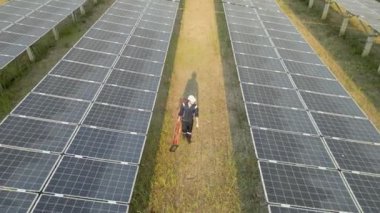 Güneş panelini kontrol etmek için güneş çiftliğinde yürüyen işçilerin en iyi görüntüsü. İHA uçuşu güneş panelleri üzerinde uçar yenilenebilir yeşil enerji alanı üzerinde.