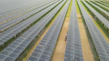 Güneş çiftliğindeki güneş panelini kontrol eden işçilerin en üst görüntüsü. İHA uçuşu güneş panelleri üzerinde uçar yenilenebilir yeşil enerji alanı üzerinde.