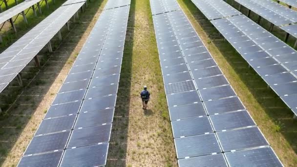 太陽光発電所をチェックするために太陽光発電所を歩く労働者のトップビュー 太陽光パネルフィールド上のドローン飛行再生可能な緑の代替エネルギー — ストック動画