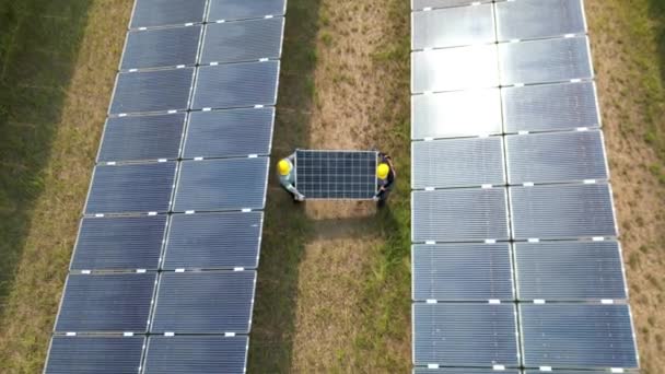 ソーラーパネルを持っている労働者のトップビューと太陽光発電所を歩く 太陽光パネルフィールド上のドローン飛行再生可能な緑の代替エネルギー — ストック動画