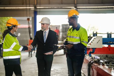 Kıdemli patron mühendis yardımcısı kadın ve Afrikalı adam konuşuyor. Ekip mühendisliği teftişi denetleme denetlemesi ağır makine inşaatı tesisi patron müdürüyle birlikte endüstriyel fabrikada..