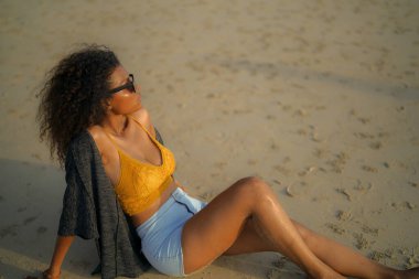 Afrikalı kadın sahilde oturuyor. Seksi Afrikalı kadın portresi tropikal doğayla yaz aylarında gezip dinleniyor..