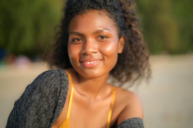 Tropik plajda bankta oturan Afrikalı bir kadın. Sarı bikini giyen ve doğanın güzelliğini ürperten genç bir gezgin. Seyahat ve seyahat kavramı. 