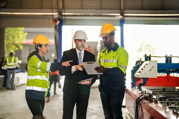 Senior boss manager talking staff engineer assistant woman and African man.Team engineering inspection check control heavy machine construction installation in industrial factory with boss manager.