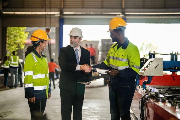 Senior boss manager talking staff engineer assistant woman and African man.Team engineering inspection check control heavy machine construction installation in industrial factory with boss manager.