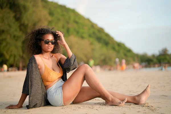 African woman sit on the beach. Portrait sexy African lady travel ping and relaxing in the summer with tropical nature.