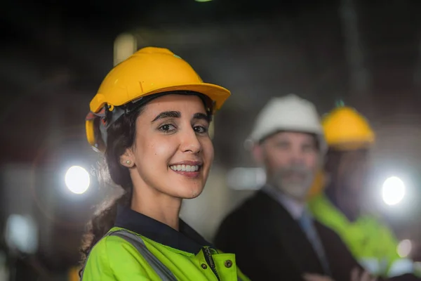 Portrait of woman worker beautiful face with eye confident and wearing working suite dress and safety helmet at heavy machine in industry factory. Brazilian worker concentrate on workplace.