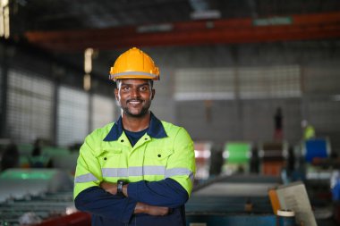 Fabrika mühendisi Afrikalı adam dizüstü bilgisayarla kendine güveniyor. İşçi, sanayi fabrikasındaki ağır makinede çalışıyor. Makine teçhizatı ile bitki teknolojisi.