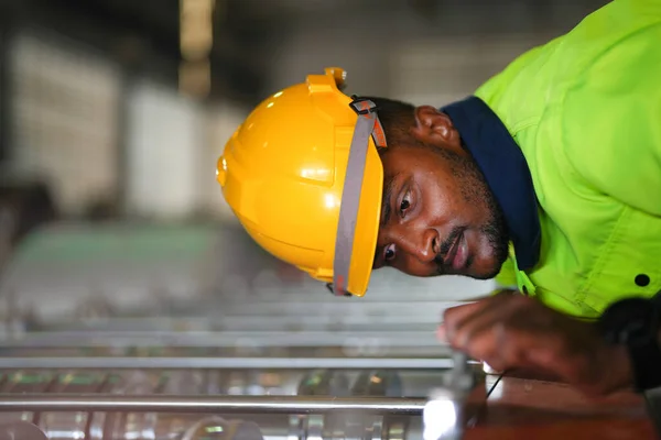 Factory engineer African man checking and reparing mahine at heavy factory.Worker works at heavy machine at industry factory. with machinery equipment plant technology.