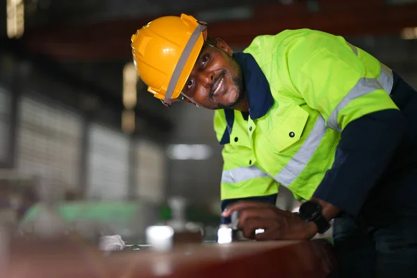 Factory engineer African man checking and reparing mahine at heavy factory.Worker works at heavy machine at industry factory. with machinery equipment plant technology.