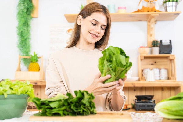 Young woman preparing healthy food with salad vegetables. woman sitting at pantry in a beautiful interior kitchen. The clean diet food from local products and ingredients Market fresh.